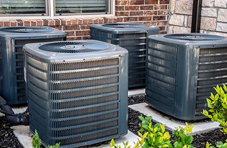 Four large outdoor HVAC units on individual concrete pads.