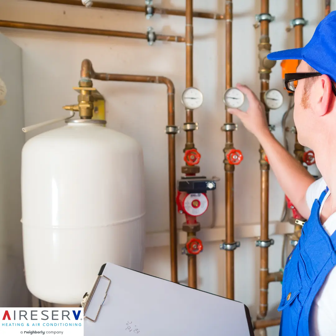 A technician checks a pressure gauge on a copper pipe system.
