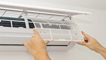 Close-up of a person's hands carefully replacing filter in wall mounted mini split AC.