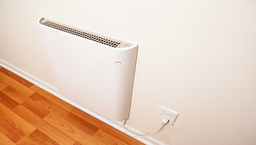 Convection heater plugged into wall socket in bright interior.