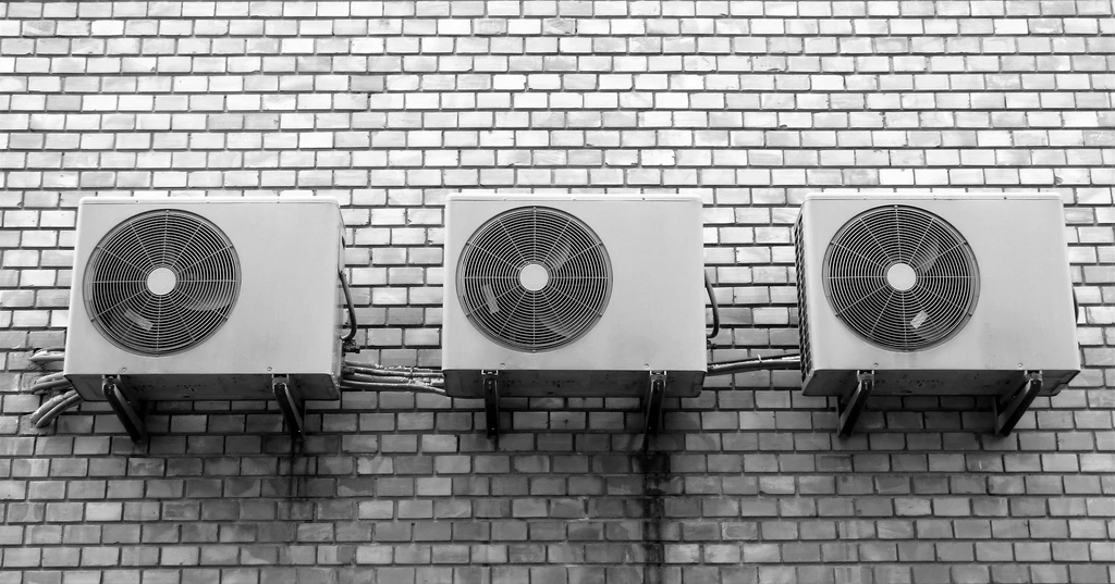 A row of three commercial AC units on the white exterior wall of a business after receiving commercial air conditioner repairs.