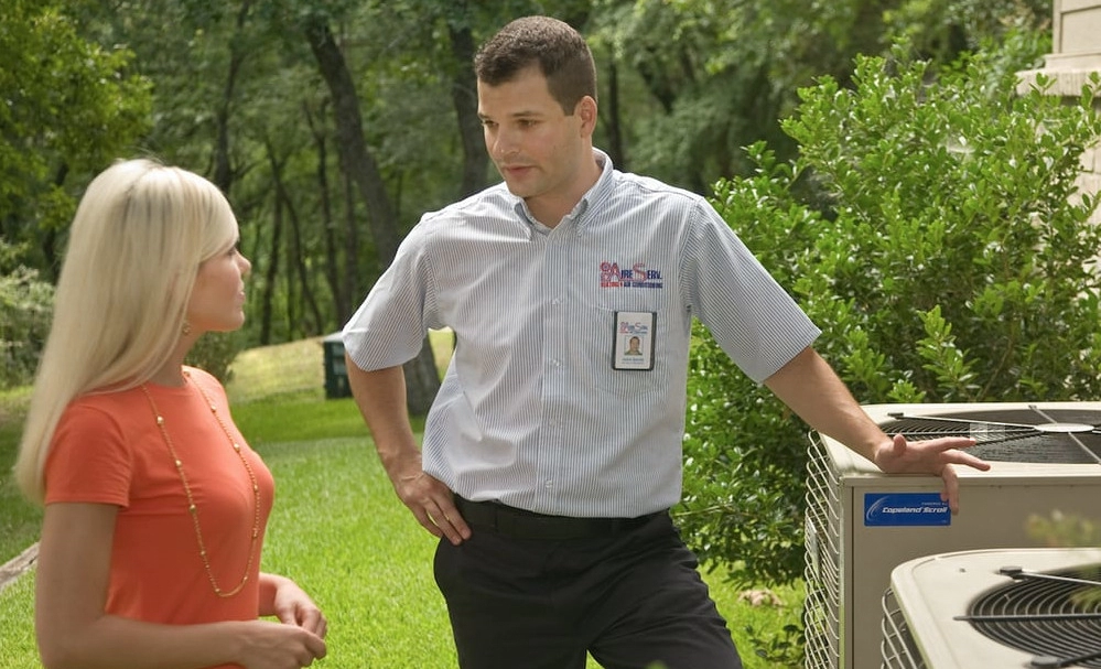A woman speaking with an HVAC service professional about whether her outdoor AC condensers need HVAC replacement in Dallas, TX.