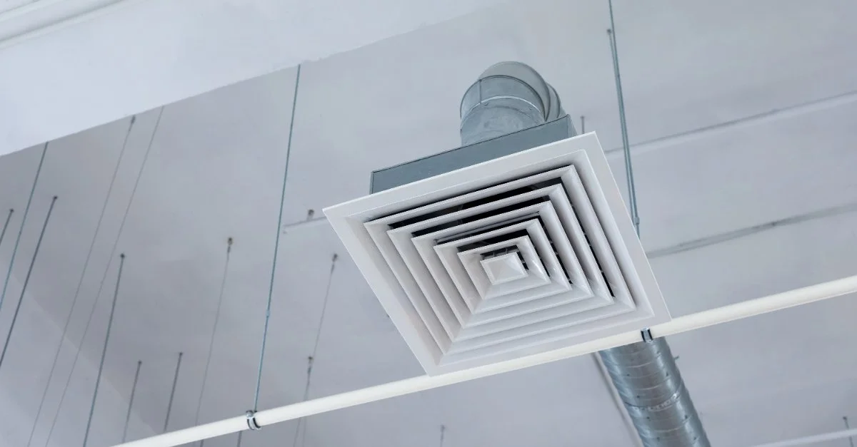 A commercial exhaust fan vent on the ducts hanging underneath the ceiling of a commercial building.