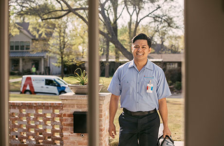 A friendly Aire Serv tech walking up to a front door before performing furnace repair