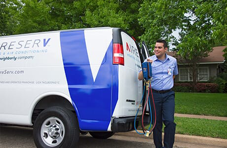 Friendly Aire Serv tech grabbing a refrigerant charging hose and gauge set from his van