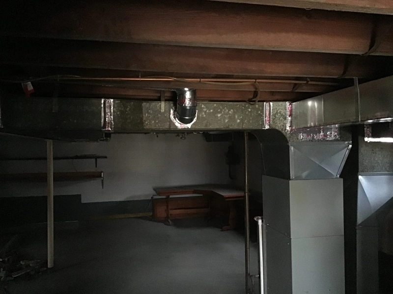 New, rigid air ducts installed along the ceiling of an unfinished basement by Aire Serv.