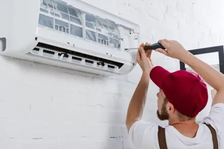HVAC technician fixing a mini-split AC unit on a wall