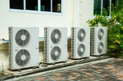 Four outdoor HVAC units installed next to the wall of a building