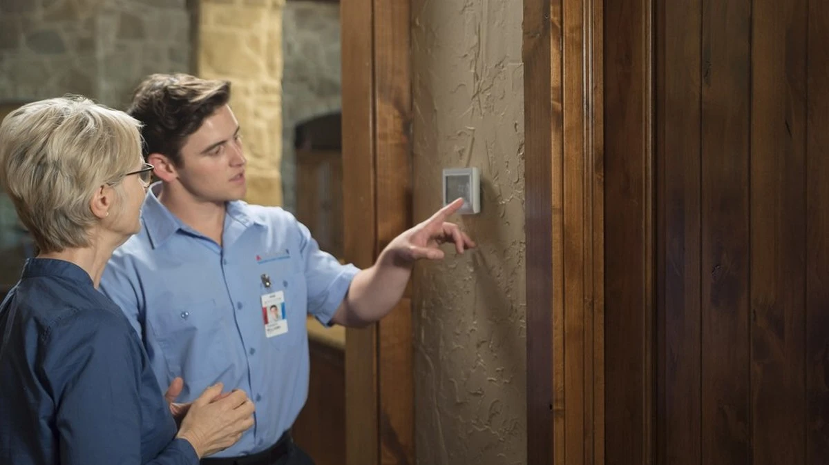 A Lucas HVAC service professional examining a thermostat with a homeowner.