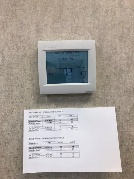 Brand new thermostat installed in McKinney home with paper explaining programmed settings.